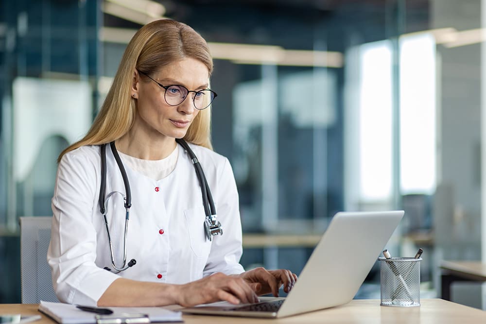 Female doctor sitting at a desk working on a laptop