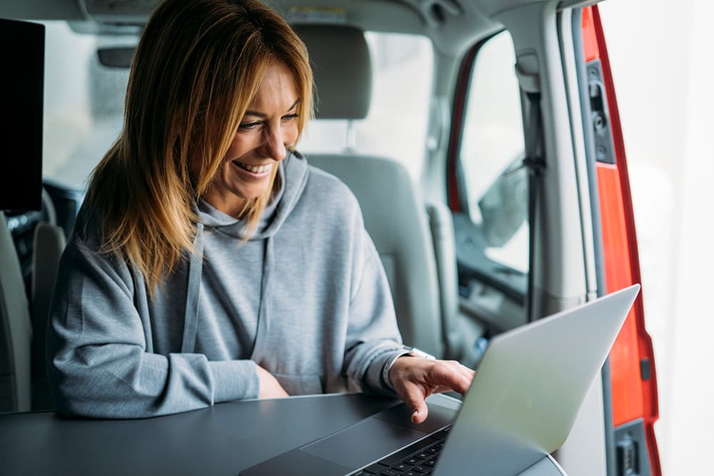 a woman smiling while using a laptop learning about SEO website copywriting